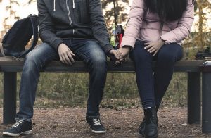 Bilden tagen från nätet. Visar ett ungt par som sitter på en bänk och håller varandra i händerna.